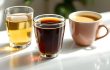 白いカウンターの上に並んだ3種類のノンカフェインドリンク。ルイボスティー、ごぼう茶、たんぽぽコーヒーが異なるカップに注がれている。